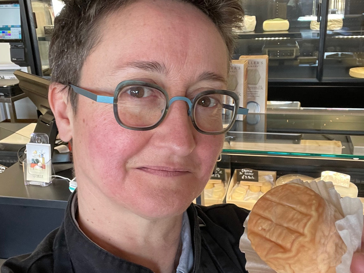 Emmanuelle Metz, Metz Cheesemonger founder, holding a soft-rind cheese at her Leeds shop counter