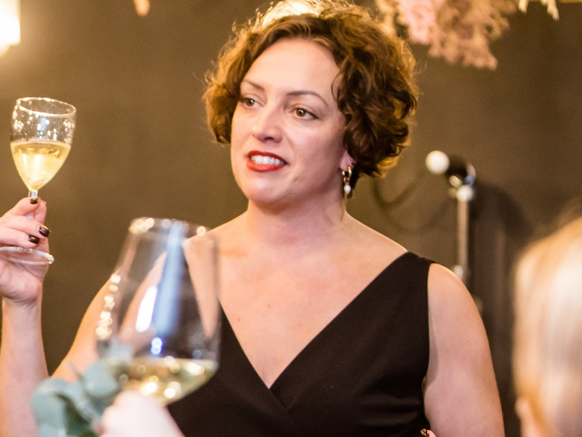Emma Moore raising glass of white wine with guests