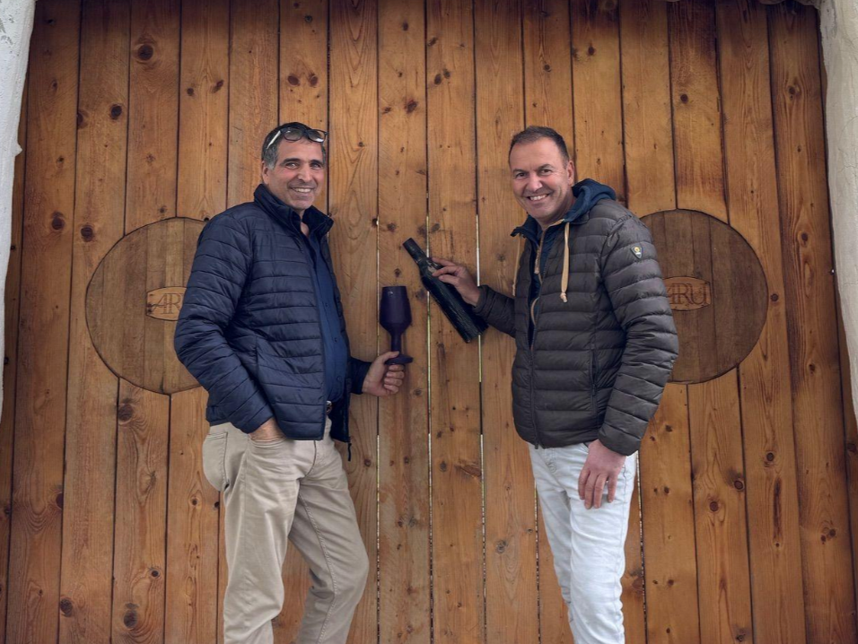 Aru Winery owner Mario Aru standing infront of solid wooden gates with friend Marco