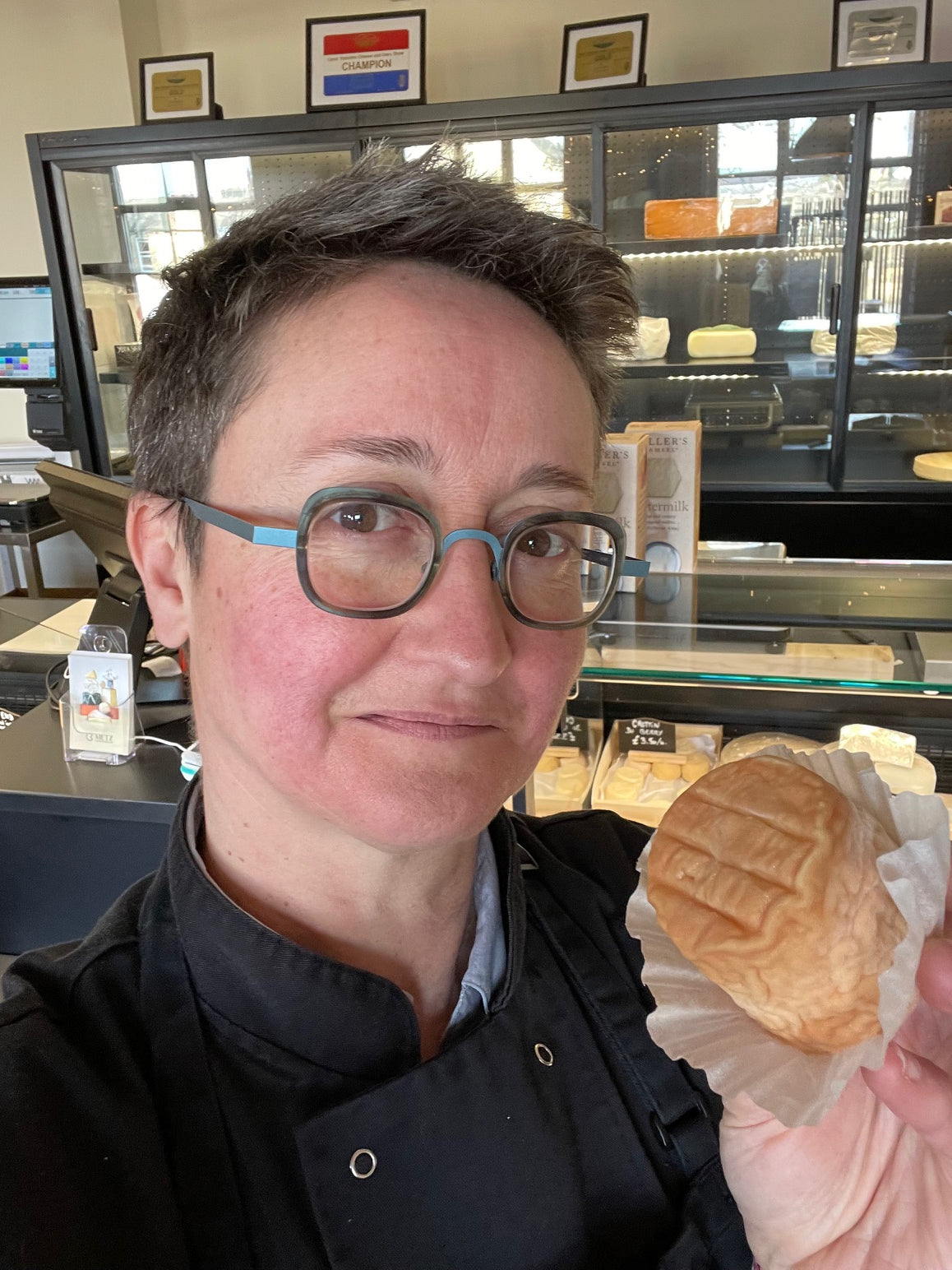 Emmanuelle Metz, Metz Cheesemonger founder, holding a soft-rind cheese at her Leeds shop counter