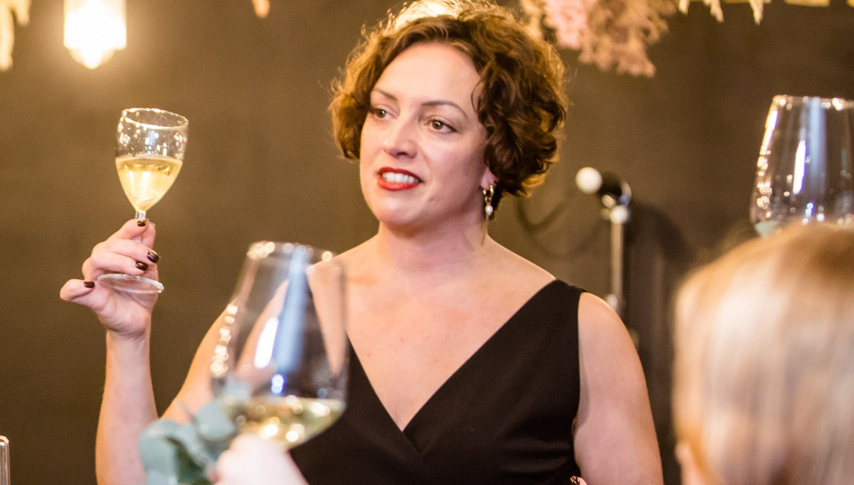Emma Moore raising glass of white wine with guests