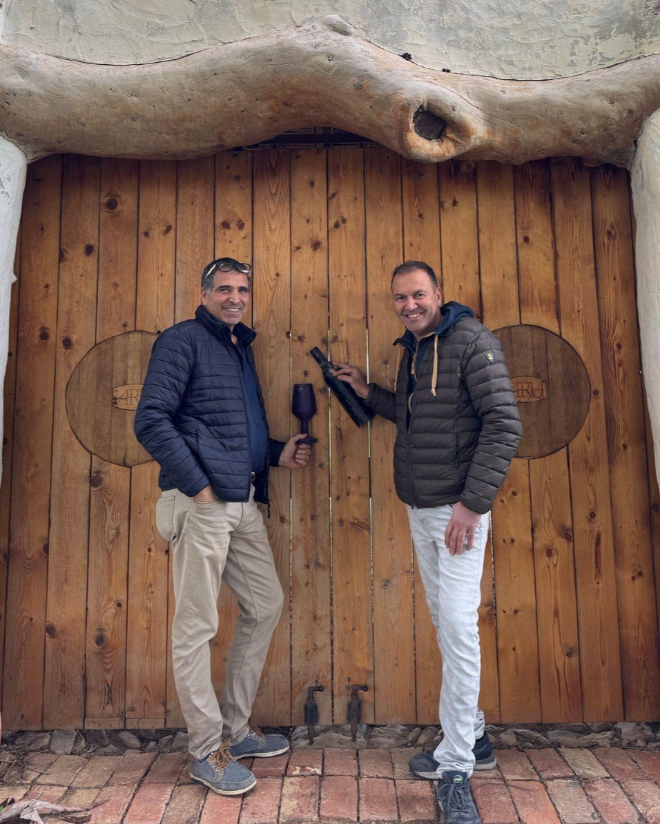 Aru Winery owner Mario Aru standing infront of solid wooden gates with friend Marco